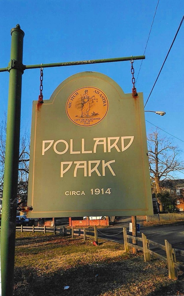 Sign for Pollard Park, established circa 1914, hanging from a green post, under a clear blue sky.